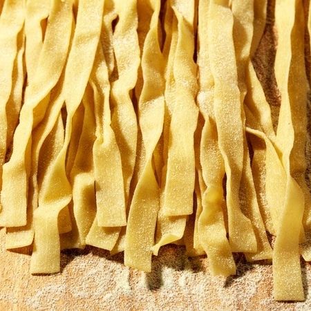 Ein Haufen Pappardelle Nudeln auf einer Holzoberfläche