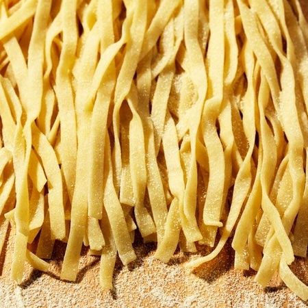 Frische Tagliatelle auf einem Holzbrett angeordnet