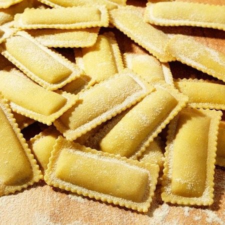 Nahaufnahme und Zubereitung von Ravioloni (Sorte: Tartufo) auf einem Holzbrett