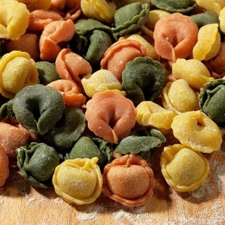 Nahaufnahme und Zubereitung von Tortellini (Sorte: Mix) auf einem Holzbrett