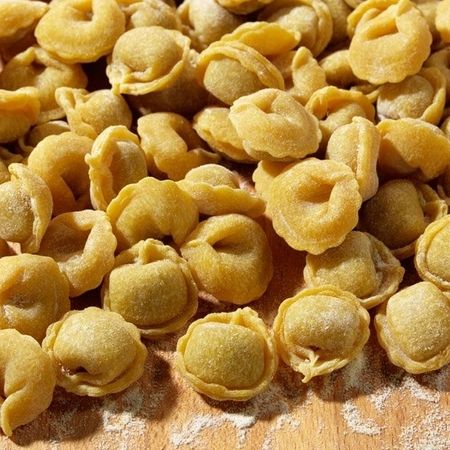 Nahaufnahme und Zubereitung von Tortellini auf einem Holzbrett