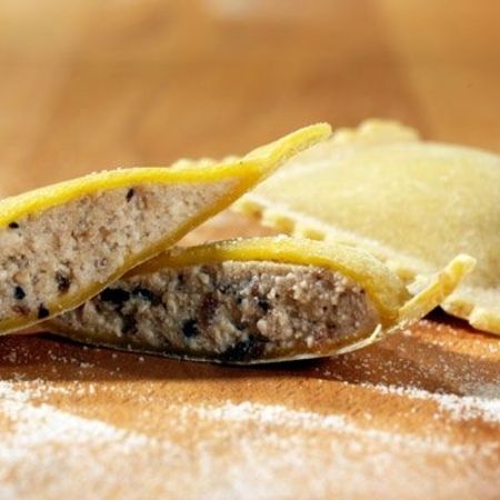 Nahaufnahme und Zubereitung von Ravioli (Sorte: Steinpilz) auf einem Holzbrett