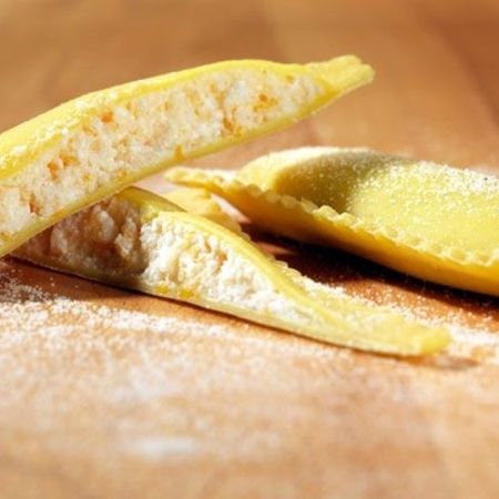 Nahaufnahme und Zubereitung von Ravioloni (Sorte: Hummer, Weiß) auf einem Holzbrett