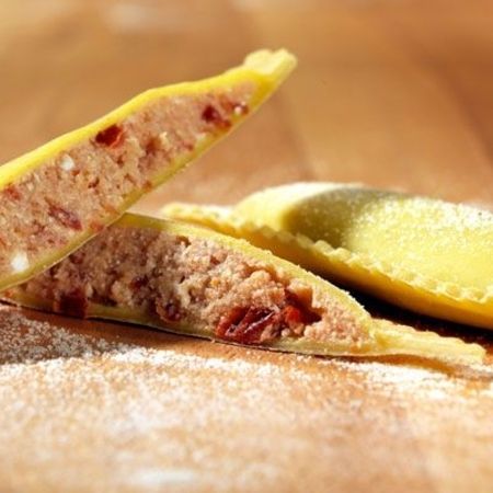 Nahaufnahme und Zubereitung von Ravioloni (Sorte: Tomate) auf einem Holzbrett