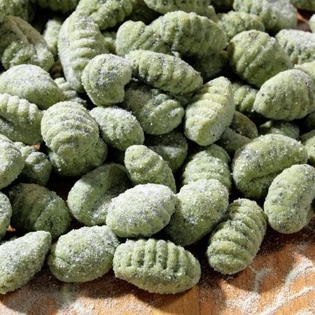Frische grüne Gnocchi auf einem mit Mehl bestäubten Holzbrett