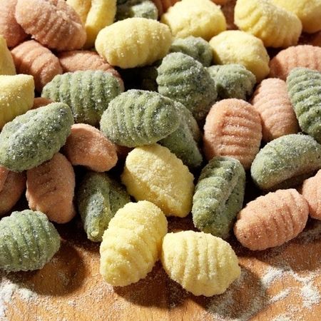 Bunte Gnocchi-Mischung auf einem Holzbrett mit Mehl