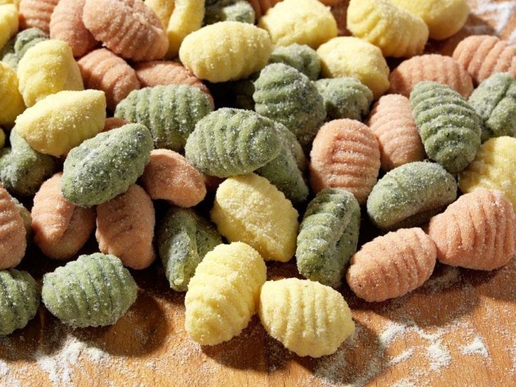 Bunte Gnocchi-Mischung auf einem Holzbrett mit Mehl