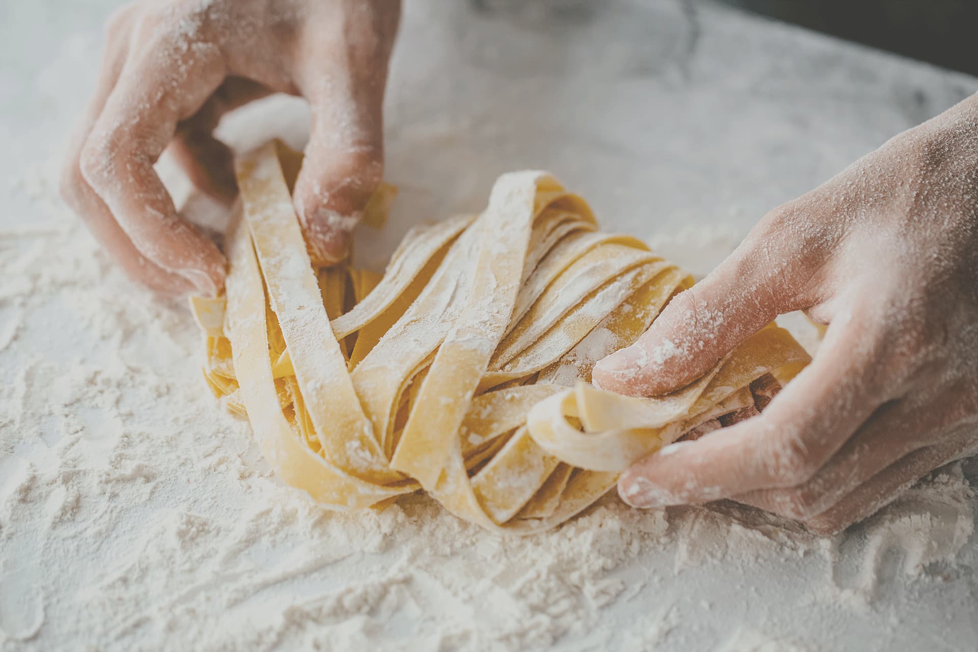 Frische Tagliatelle werden in Mehl gewendet