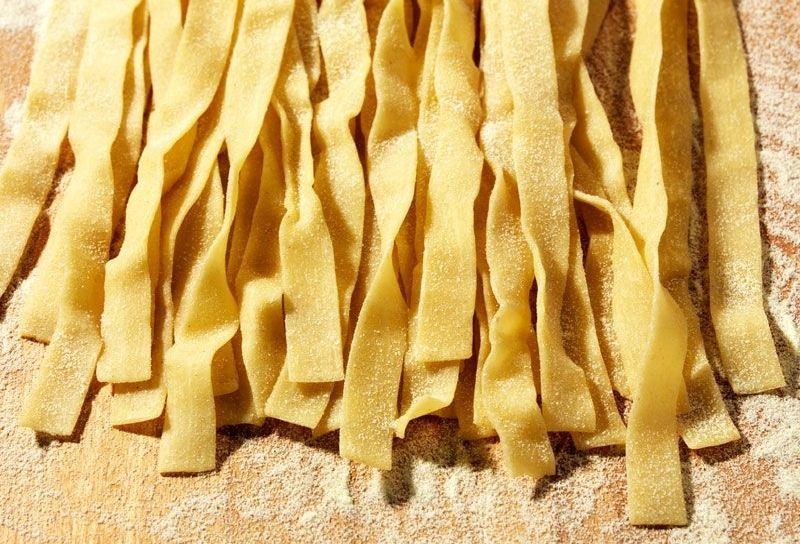 Ein Haufen Pappardelle Nudeln auf einer Holzoberfläche