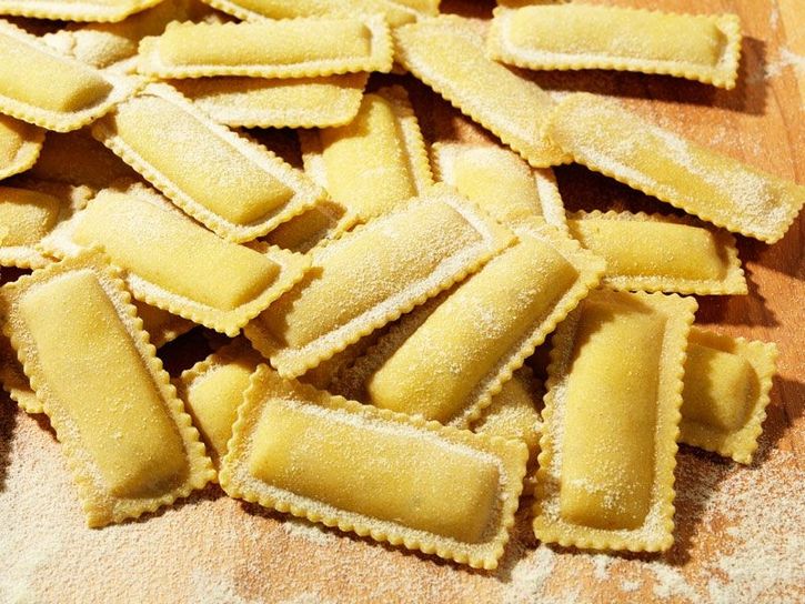 Nahaufnahme und Zubereitung von Ravioloni (Sorte: Tartufo) auf einem Holzbrett
